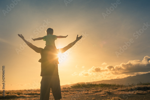 Father son having fun outdoors at sunset pretending to fly. Family adventure and freedom concept.