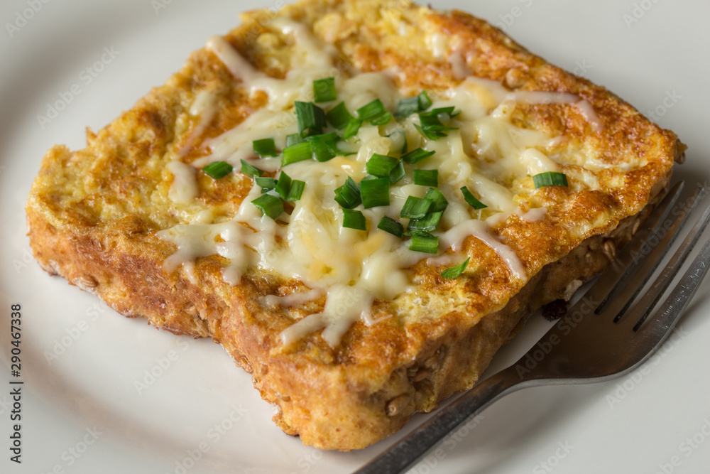 Savoury French toast topped with chopped green spring onions and melted cheese Savoury French toast topped with chopped green spring onions and melted cheese