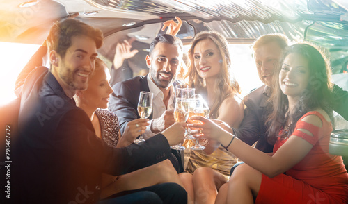 Group of women and men clinking glasses in a limousine