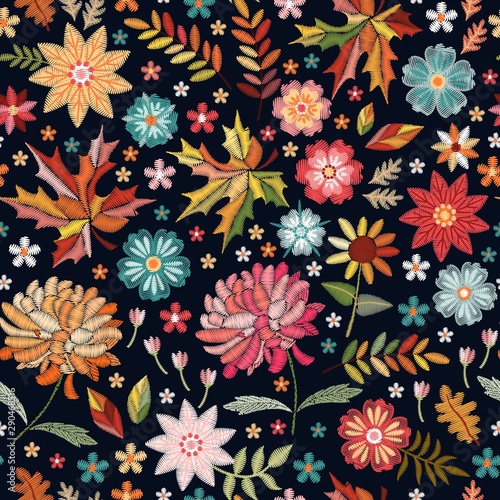 Colorful embroidery pattern. Seamless design with bright flowers and leaves on black background.