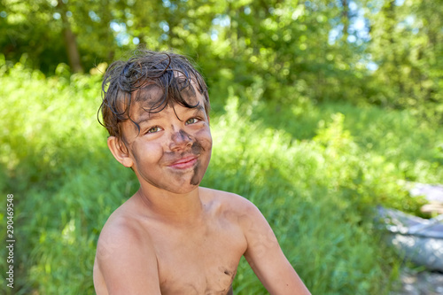 TPortrait of a happy child smeared with dirt on nature photo