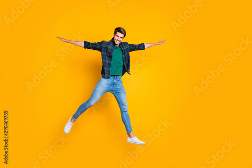 Full length photo of cheerful funny positive man jump hold hand like wings enjoy weekends summer spring holidays wear god-looking outfit isolated over yellow color background © deagreez
