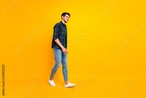 Full length body size photo of cheerful attractive guy walking towards sales wearing sneakers isolated over yellow vivid color background