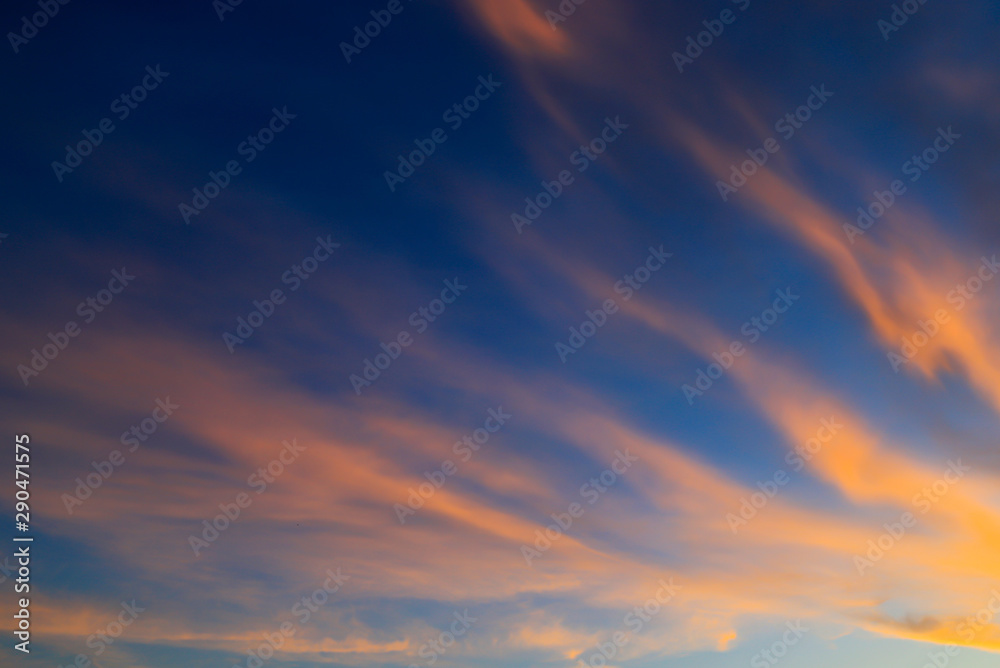 Beautiful orange feather clouds on a blue sky at sunset, magical background, autumn, spring, summer. Weather forecast, atmosphere. Landscape clouds for poster, astrology horoscope