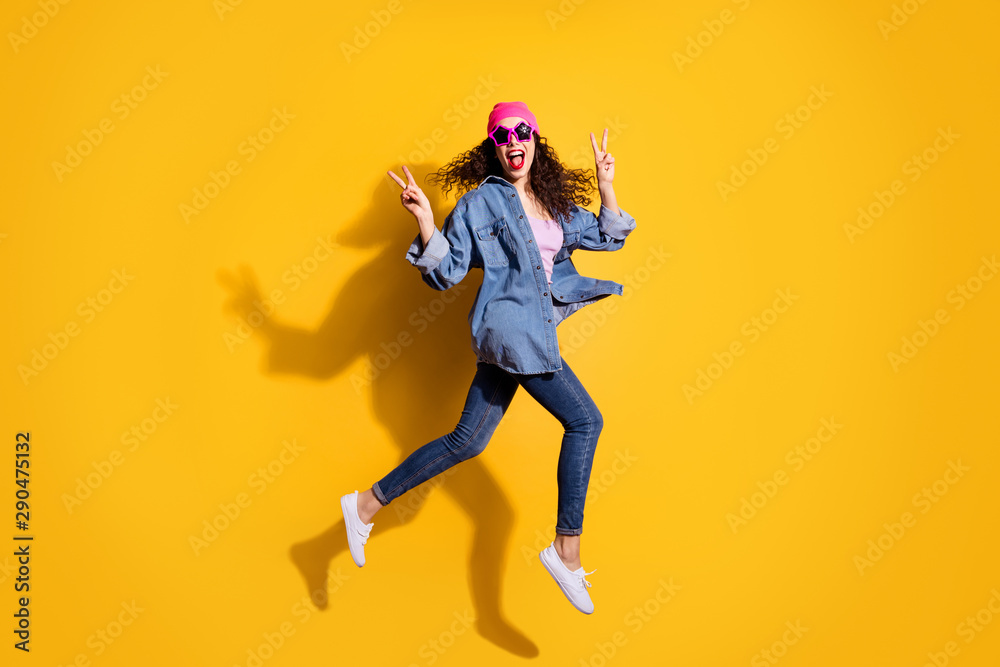 Full length photo of funky curly lady jumping high going to party showing v-sign symbols wear casual trendy clothes isolated yellow color background