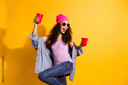 Photo of stylish lady raising red cups with beer at student party moving rhythm Fototapet