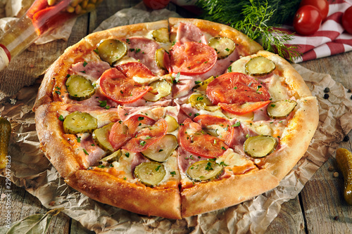 Pizza Restaurant Menu - Delicious Fresh Pizza with Tomato, Ham and Pickled Cucumber. Pizza on Rustic Wooden Table with Ingredients
