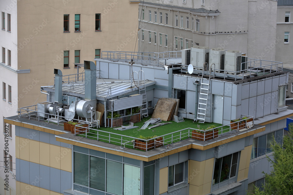 Roof of a small city building with chimneys, air conditioning and ventilation equipment Roof of a small city building with chimneys, air conditioning and ventilation equipment