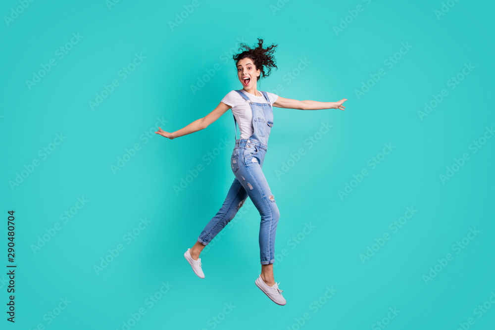 Full length body size view of her she nice attractive cheerful cheery crazy girl wearing blue overall jumping having fun isolated on bright vivid shine vibrant green turquoise background