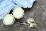  Greek yogurt in glass jars with spoons on a gray textural background. Top view. Diet product concept.