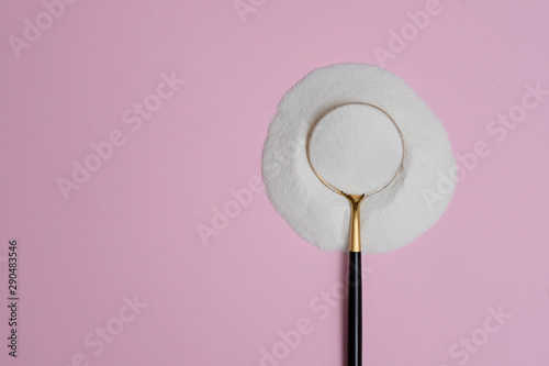 collagen protein powder on a modern spoon on pink background