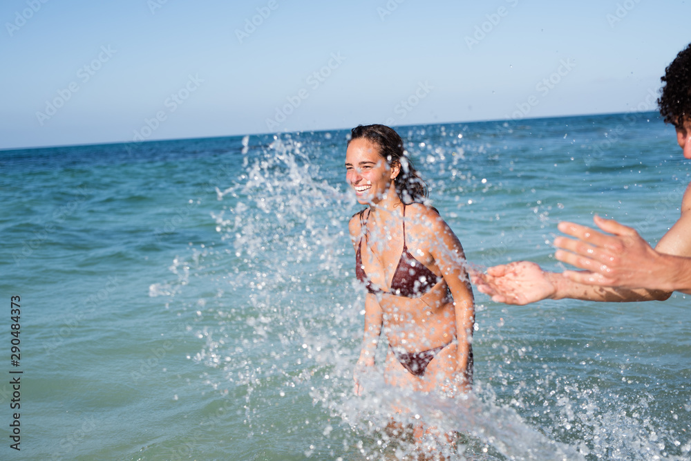 Young man splashing a young girl with water