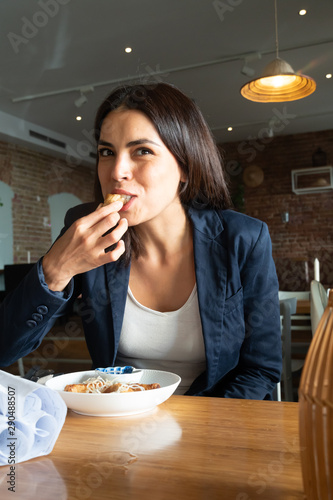 Young beautiful brunette woman biting food in an Asian restaurant