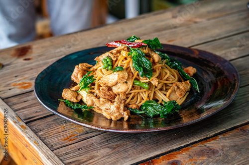 Stir Fry spaghetti with chicken and hearbs in black bowl