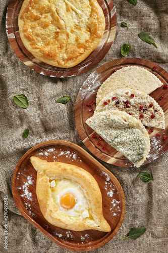 Set of Georgian and Adjarian Khachapuri Dishes, Kutabs and Chebureks on Rustic Tablecloth Burlap Background