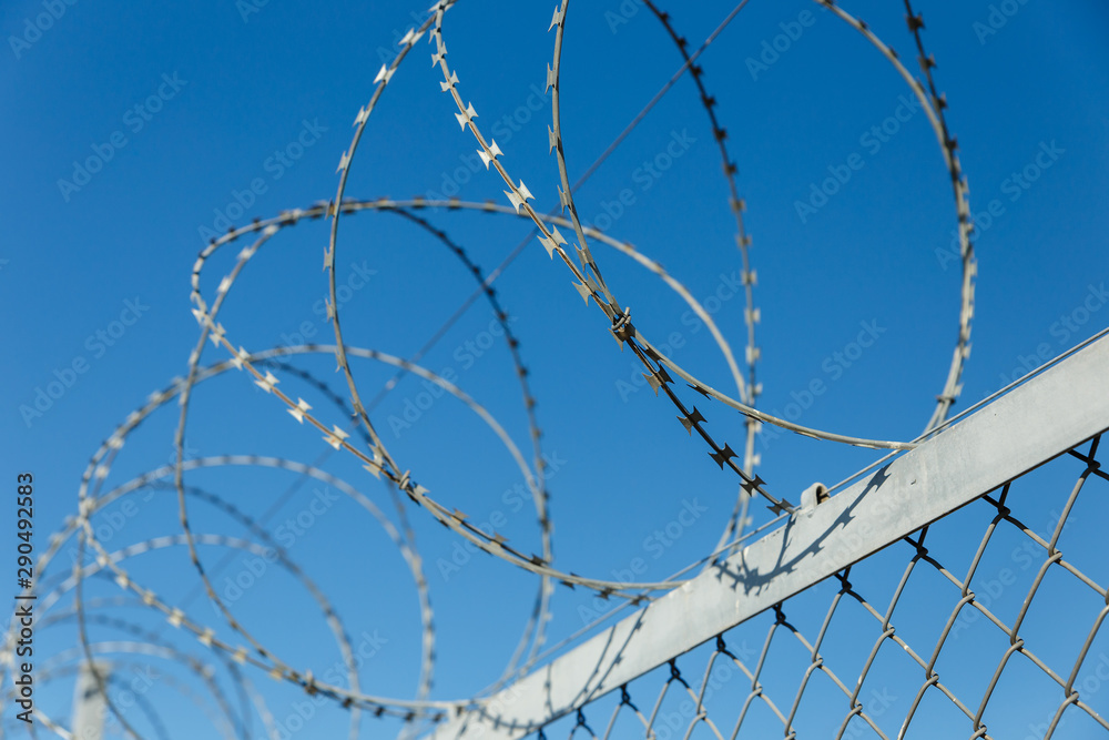 fence with barbed wire, barbed wire against the blue sky fence with barbed wire, barbed wire against the blue sky