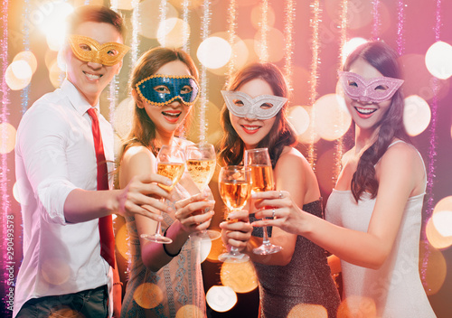happy young group celebrating New Year and drinking champagne on masquerade party