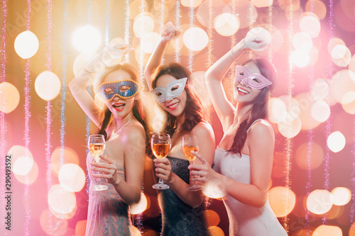 happy young group celebrating New Year and drinking champagne on masquerade party