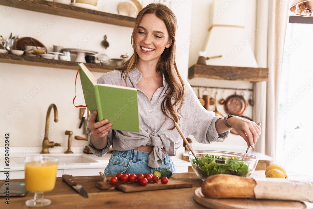 Pretty lady indoors at the kitchen cooking holding notebook. Pretty lady indoors at the kitchen cooking holding notebook.