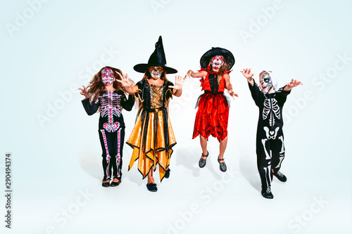 Kids or teens like witches and vampires with bones and glitter on white background. Caucasian models looks scary and playful. Halloween, black friday, sales, autumn holidays concept. The night of fear