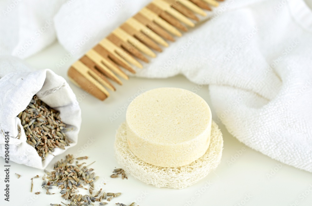 Solid shampoo bar with lavender, wooden hair comb and white towel on background, zero waste bathroom Solid shampoo bar with lavender, wooden hair comb and white towel on background, zero waste bathroom