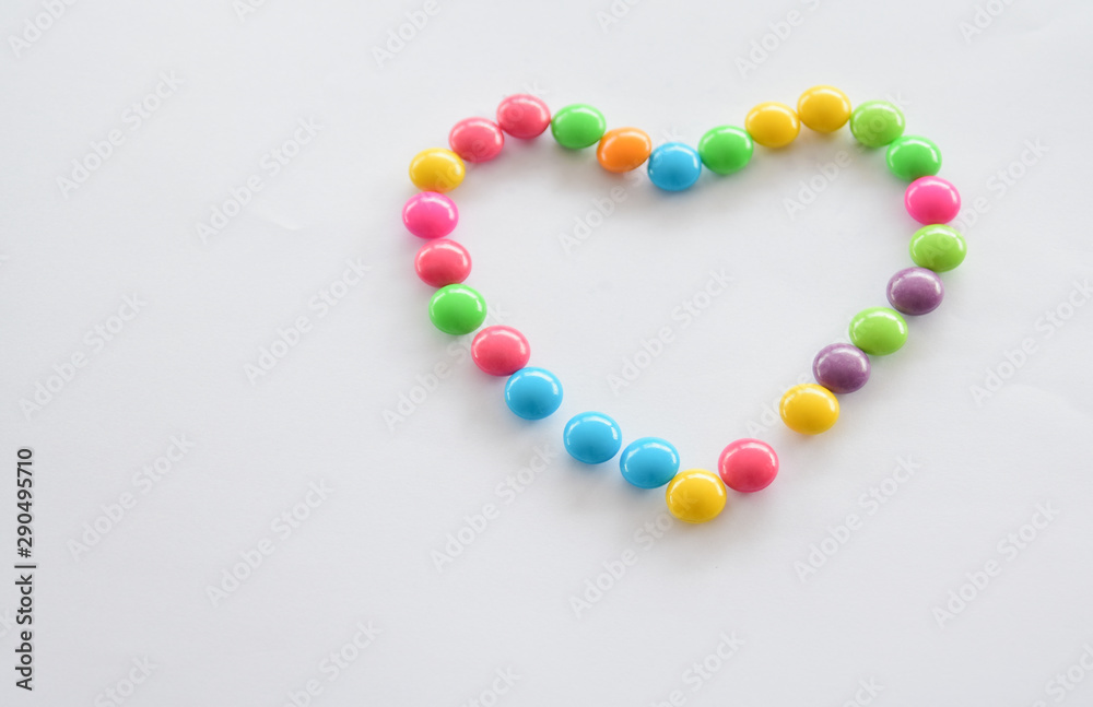 Place colorful candies into concept of heart symbol. Love and colorful concept.