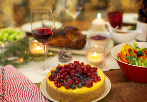 christmas dinner and eating concept - berry cake and other food on table at home