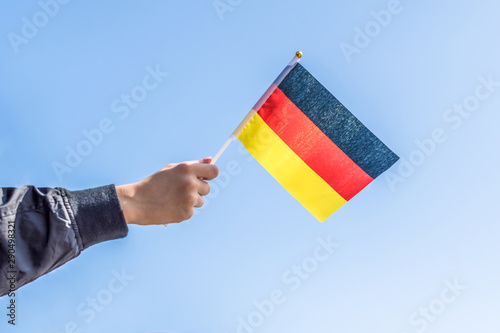 Boy holding Germany Flag on the blue sky backgrouns. Concept.