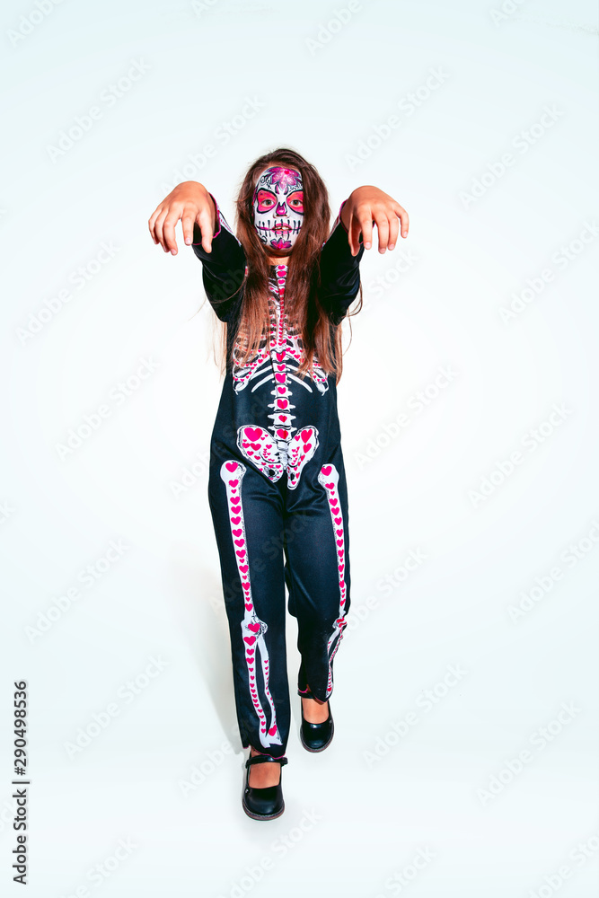 Little girl like a zombie in scary bright costume with bones on white  background. Caucasian female model looks scary. Halloween, black friday,  sales, autumn holidays concept. The night of fear. Stock Photo