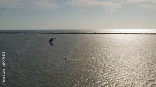 Aerial view of kitesurfer gliding and jumping across sea