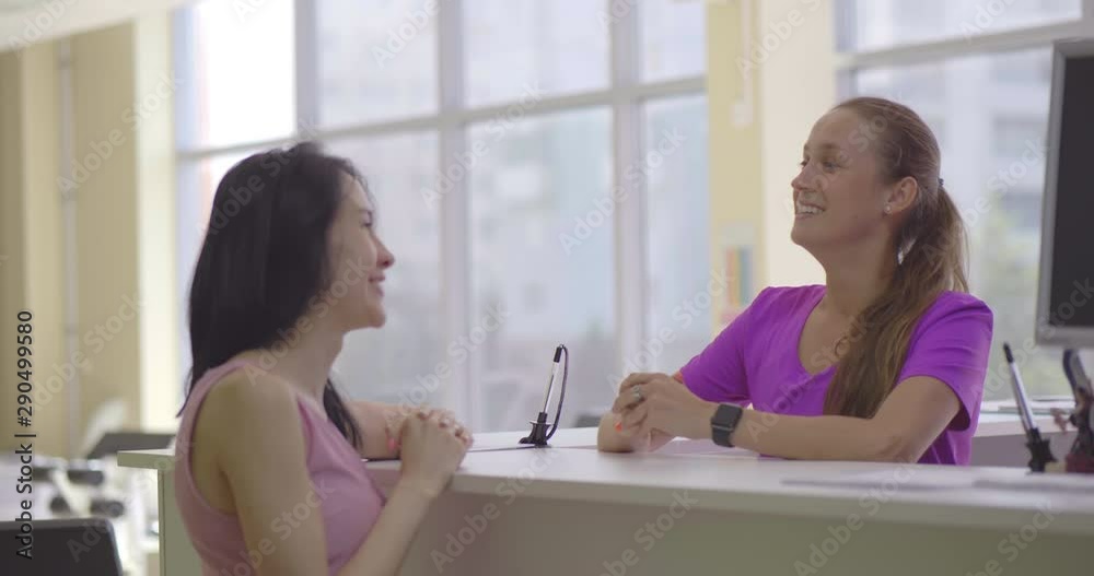 Female receptionist of the fitness center and sporty woman talk Female receptionist of the fitness center and sporty woman talk