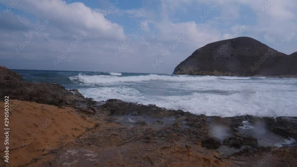 Seascape. Beach El Playazo, Cabo de Gata, province AlmerĂa, Andalusia Spain. Rocky sea shore with waves splashing in slow motion. Tourist site Seascape. Beach El Playazo, Cabo de Gata, province AlmerĂa, Andalusia Spain. Rocky sea shore with waves splashing in slow motion. Tourist site