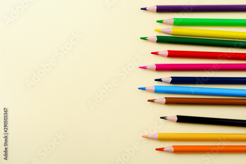 Multicolored wooden pencils for school on yellow paper background. School and office stationery on yellow background. Concept back to school. Top view.