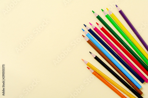 Multicolored wooden pencils for school on yellow paper background. School and office stationery on yellow background. Concept back to school. Top view.