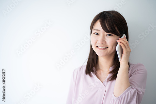 Young business woman talking on smart phone against white wall
