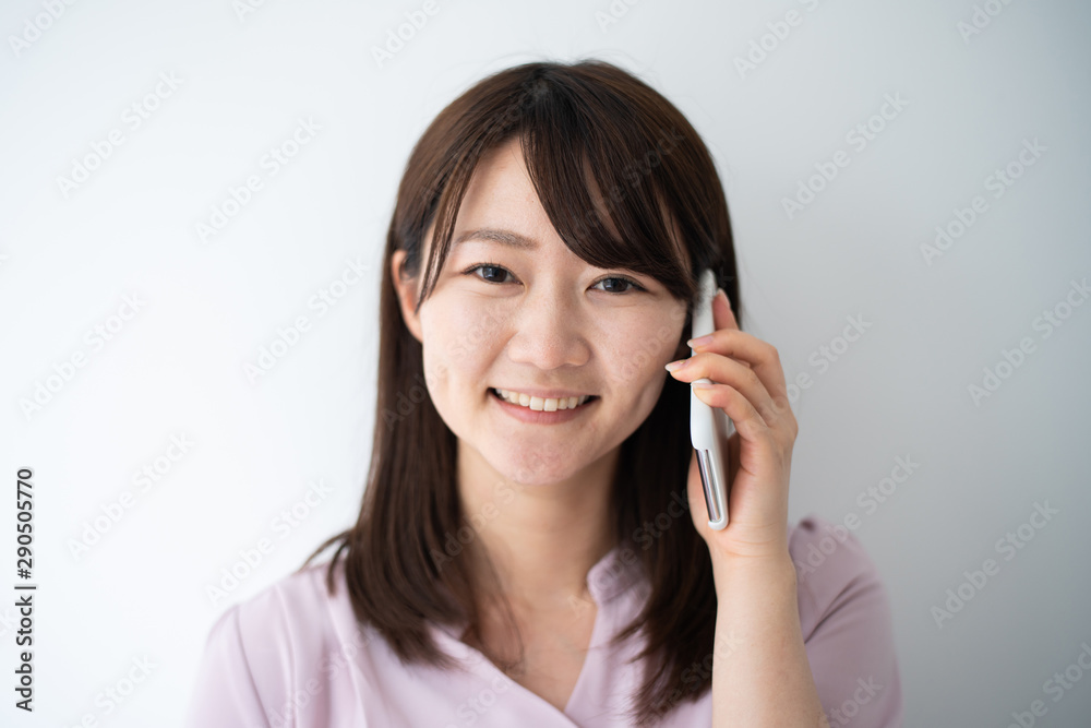 Young business woman holding smart phone against white wall Young business woman holding smart phone against white wall