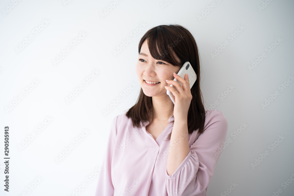 Young business woman holding smart phone against white wall Young business woman holding smart phone against white wall