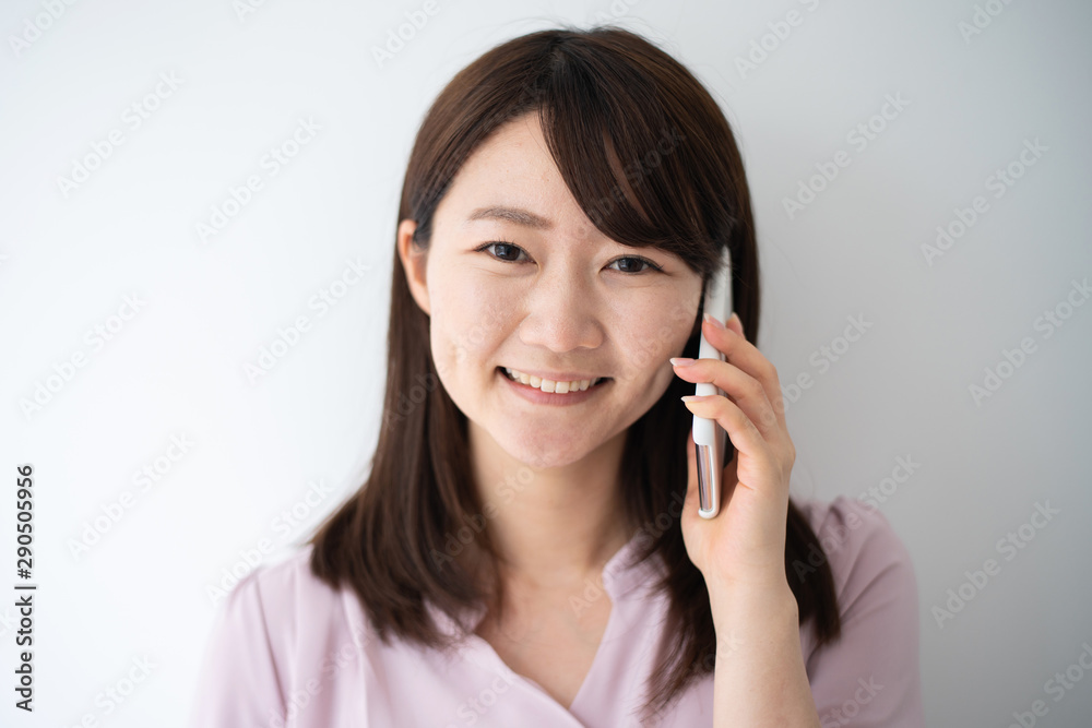 Young business woman holding smart phone against white wall Young business woman holding smart phone against white wall