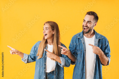 Foto Image of pleased couple man pointing fingers aside at copyspace
