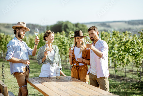 Group of young friends dressed casually having fun together, tasting wine on the vineyard on a sunny summer morning photo