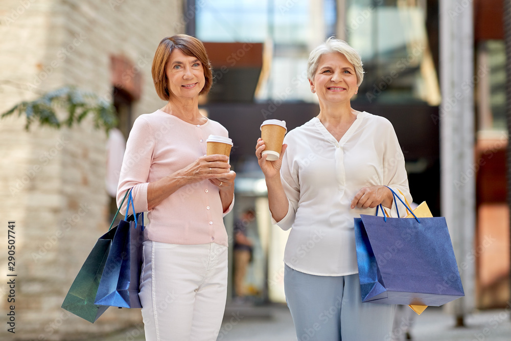 sale, consumerism and people concept - two senior women or friends with shopping bags drinking takeaway coffee on tallinn city street sale, consumerism and people concept - two senior women or friends with shopping bags drinking takeaway coffee on tallinn city street