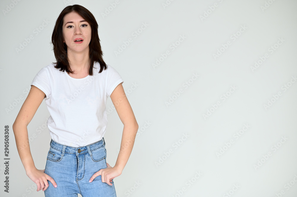 Portrait of a pretty asian brunette girl with black hair in a white t-shirt and blue jeans on a white background. It stands right in front of the camera, with emotions in various poses. Portrait of a pretty asian brunette girl with black hair in a white t-shirt and blue jeans on a white background. It stands right in front of the camera, with emotions in various poses.