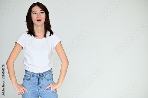 Portrait of a pretty asian brunette girl with black hair in a white t-shirt and blue jeans on a white background. It stands right in front of the camera, with emotions in various poses.