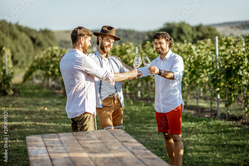 Three guys dressed casually tasting wine while spending time together on the vineyard on a sunny summer morning