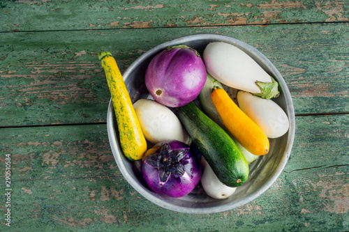 Obraz na płótnie Fresh eggplants and zucchini in basket over wooden green background