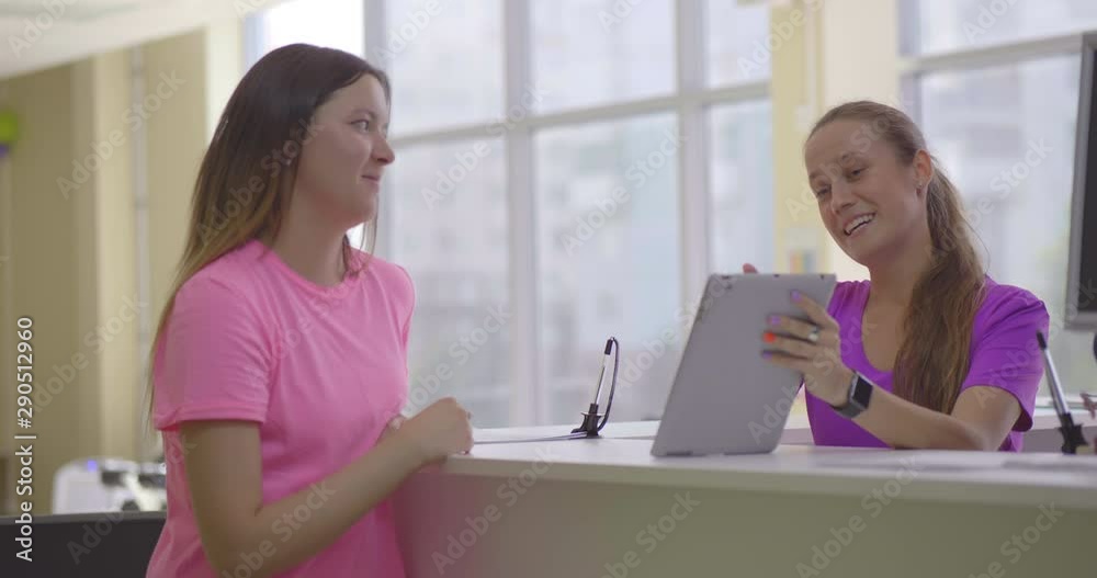 Female receptionist of fitness club and client discuss available programs of training Female receptionist of fitness club and client discuss available programs of training