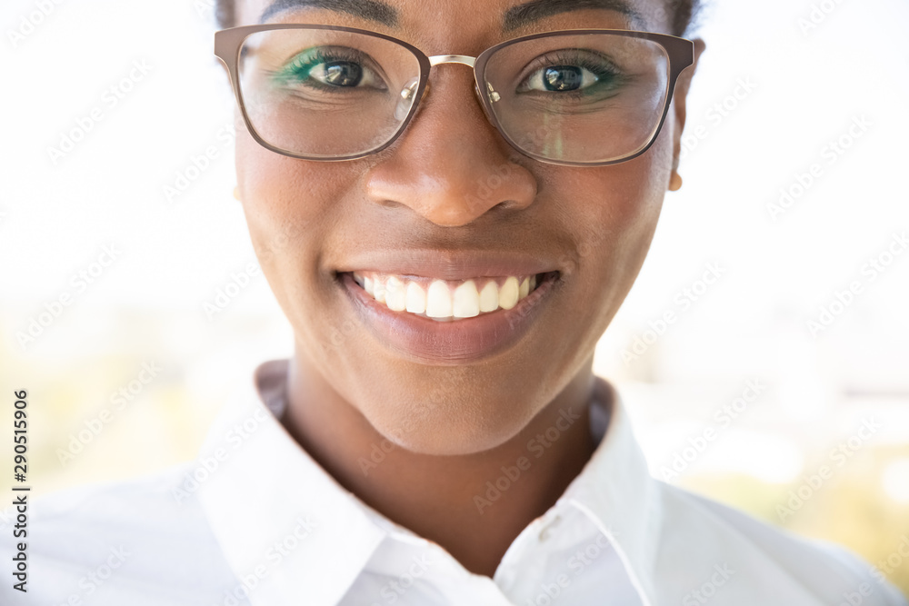 Happy face of businesswoman. Closeup of young African American business woman wearing glasses and white shirt, looking at camera and smiling. Closeup portrait concept Happy face of businesswoman. Closeup of young African American business woman wearing glasses and white shirt, looking at camera and smiling. Closeup portrait concept