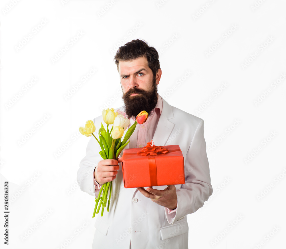 Businessman with gift and bouquet of tulips for birthday. Handsome young man holding gift box and flowers. Romantic man. Bearded man holds bouquet of flowers and gift box. Valentines Day, Womens Day. Businessman with gift and bouquet of tulips for birthday. Handsome young man holding gift box and flowers. Romantic man. Bearded man holds bouquet of flowers and gift box. Valentines Day, Womens Day.
