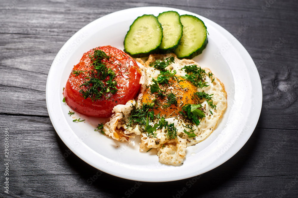 Grilled egg and grilled tomato on a plate on a wooden background. Fast and easy to prepare breakfast.