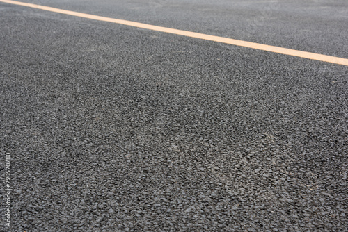 Low angle close-up of wide asphalt road and yellow paint line